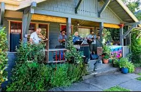 Musicians performing on the front porch of a charming historic home during a neighborhood PorchFest community music event.